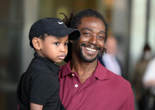 James Irons holds great-nephew Michale in 2022 after he, Thomas Malik and Vincent Ellerbe were cleared of fatally setting subway clerk Harry Kaufman on fire in his token booth in 1995.