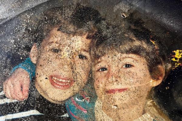 A photo of siblings that has been damaged with muck and dirt.