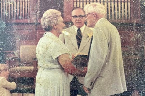 An older couple make vows in what appears to be a church.