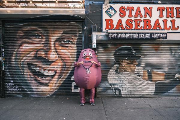 "Grimace" in front of murals of Yankee stars Derek Jeter and Aaron Judge.