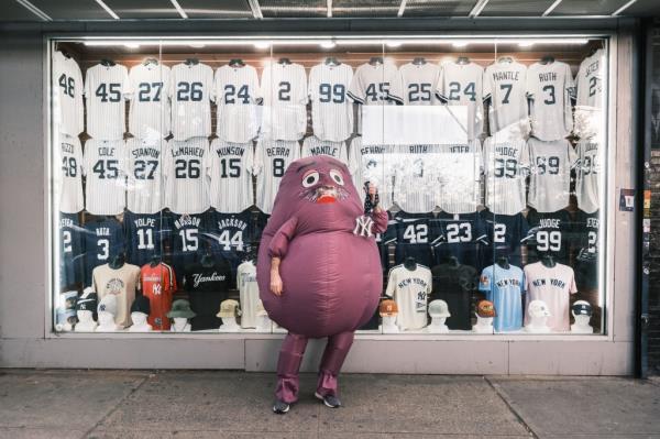 The Mets-affiliated fast food icon holds up a Yankees chain in front of a store selling Yankees merchandise.